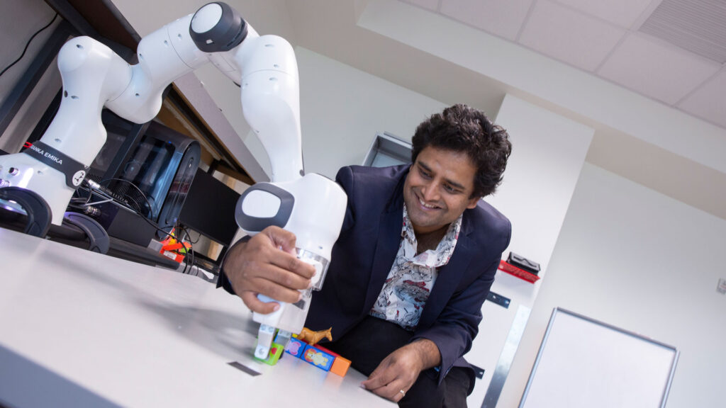 Nakul Gopalan works with a robotic arm in his lab.