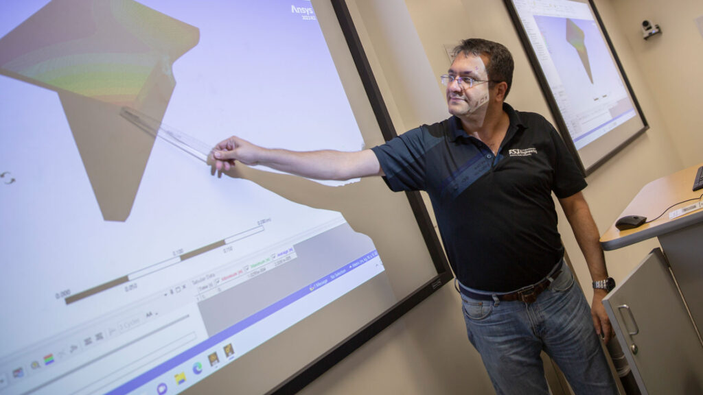Masoud Yekani Fard points to a graphic on a projector screen in a classroom.