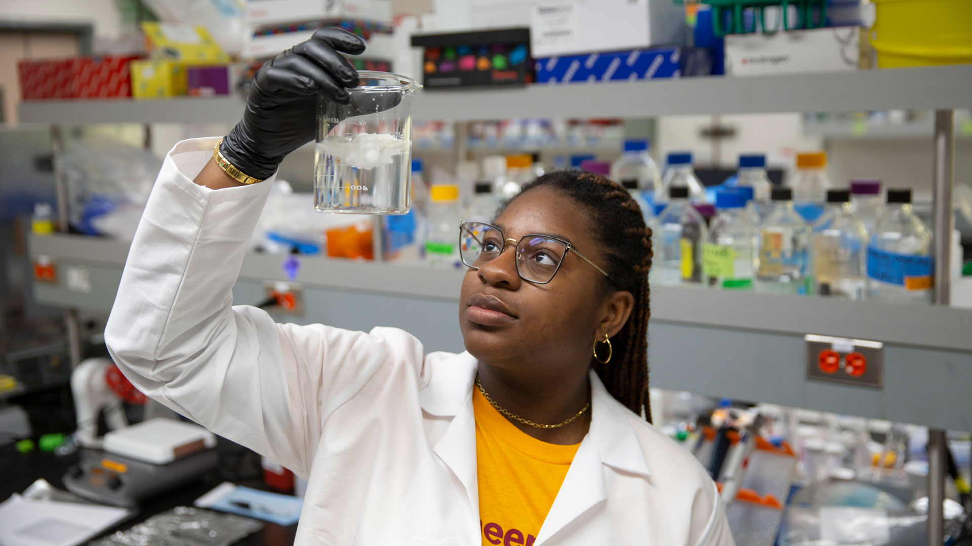 An ASU FURI student looks at a beaker.