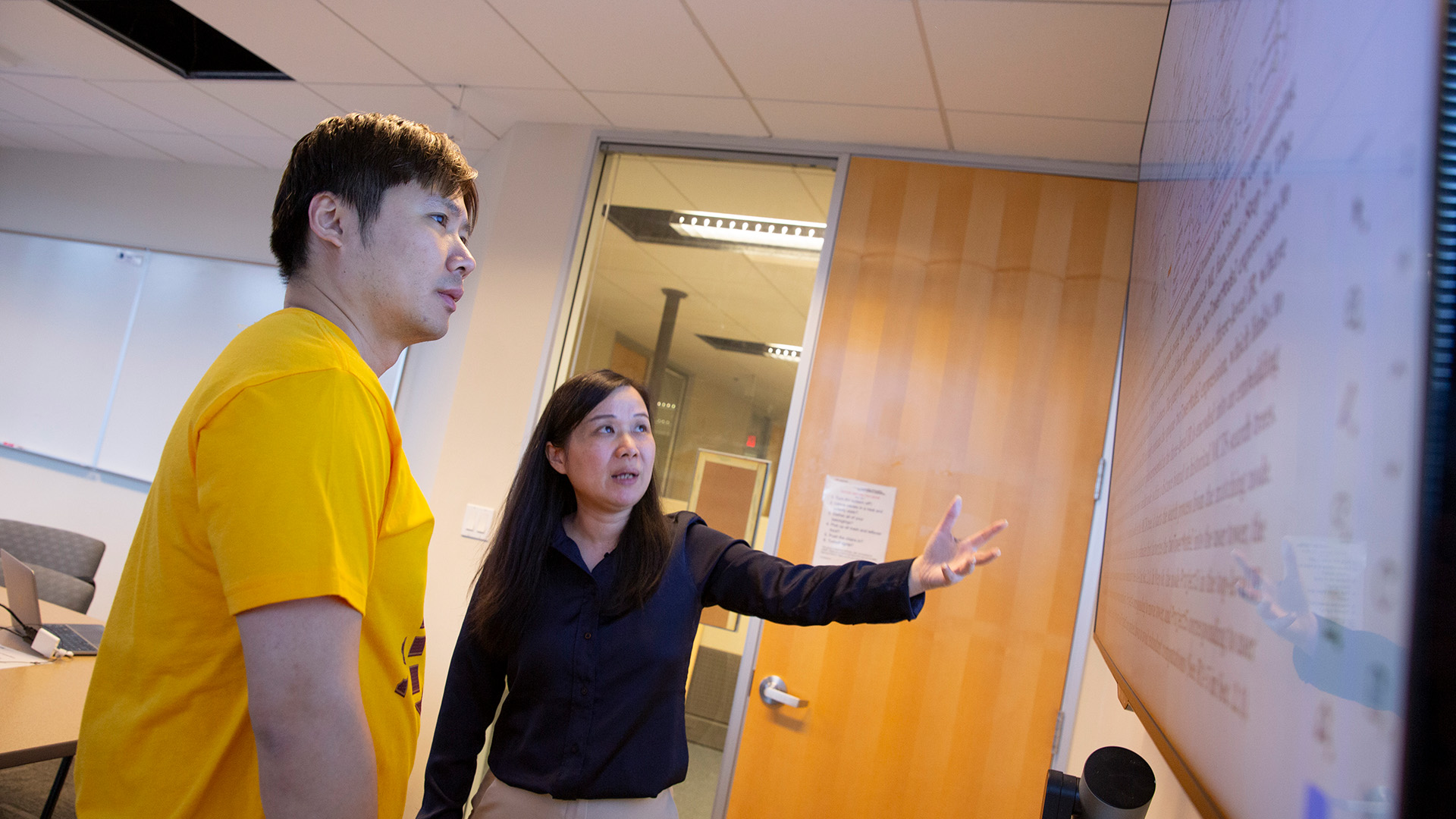 Kyle Hu and Jia Zou look at a screen