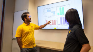 Kumar Satvik Chaudhary points at a screen as someone else looks on.