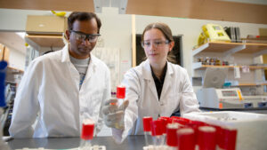 Shira Shecter and her faculty mentor look at a vial in a lab.