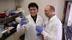 Diego Sanchez looks at green liquid in a vial while his mentor watches.