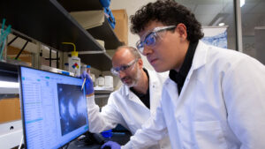 Diego Sanchez and his mentor look at a computer screen.