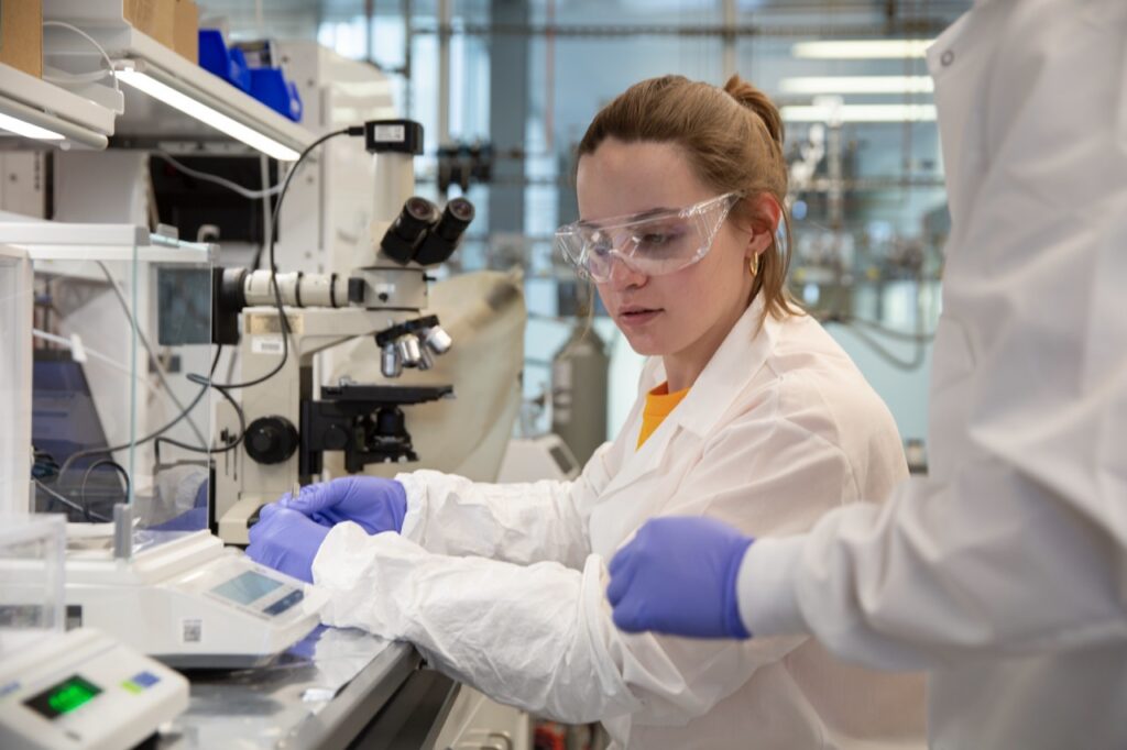 Lia Ryan works with lab equipment near a microscope
