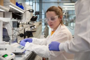 Lia Ryan works with lab equipment near a microscope